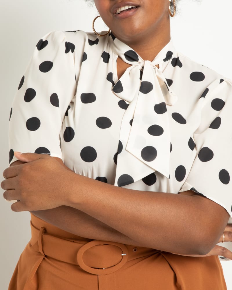 Side of a model wearing a size 20 Bow Blouse with Flutter Sleeve in Vera Dot Bone by ELOQUII. | dia_product_style_image_id:295105
